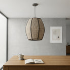 A black woven pendant light shade with a textured, ribbed pattern, suspended by a thin black cord against a plain white background.