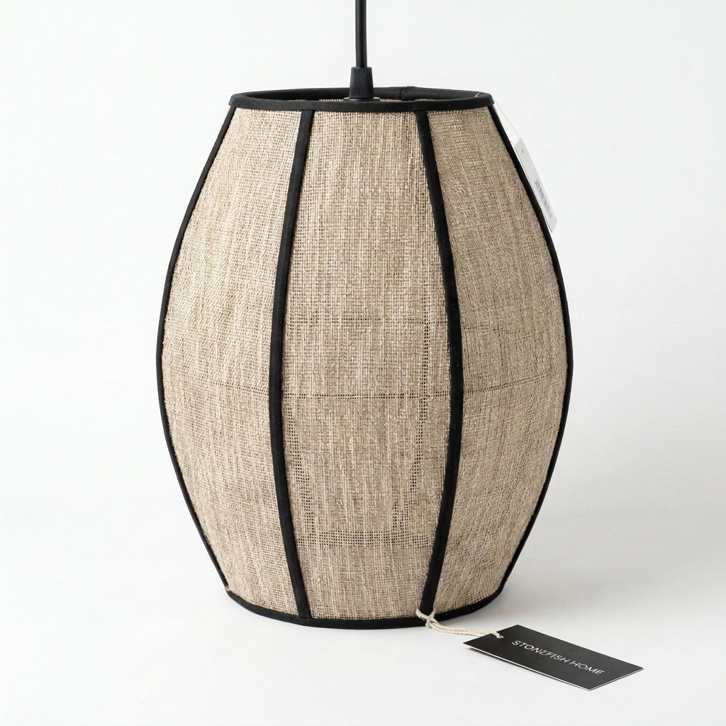 A hanging pendant lamp with a textured beige woven shade, black trim, and a black top rod, shown on a white background with a small tag in front.