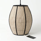 A hanging pendant lamp with a textured beige woven shade, black trim, and a black top rod, shown on a white background with a small tag in front.