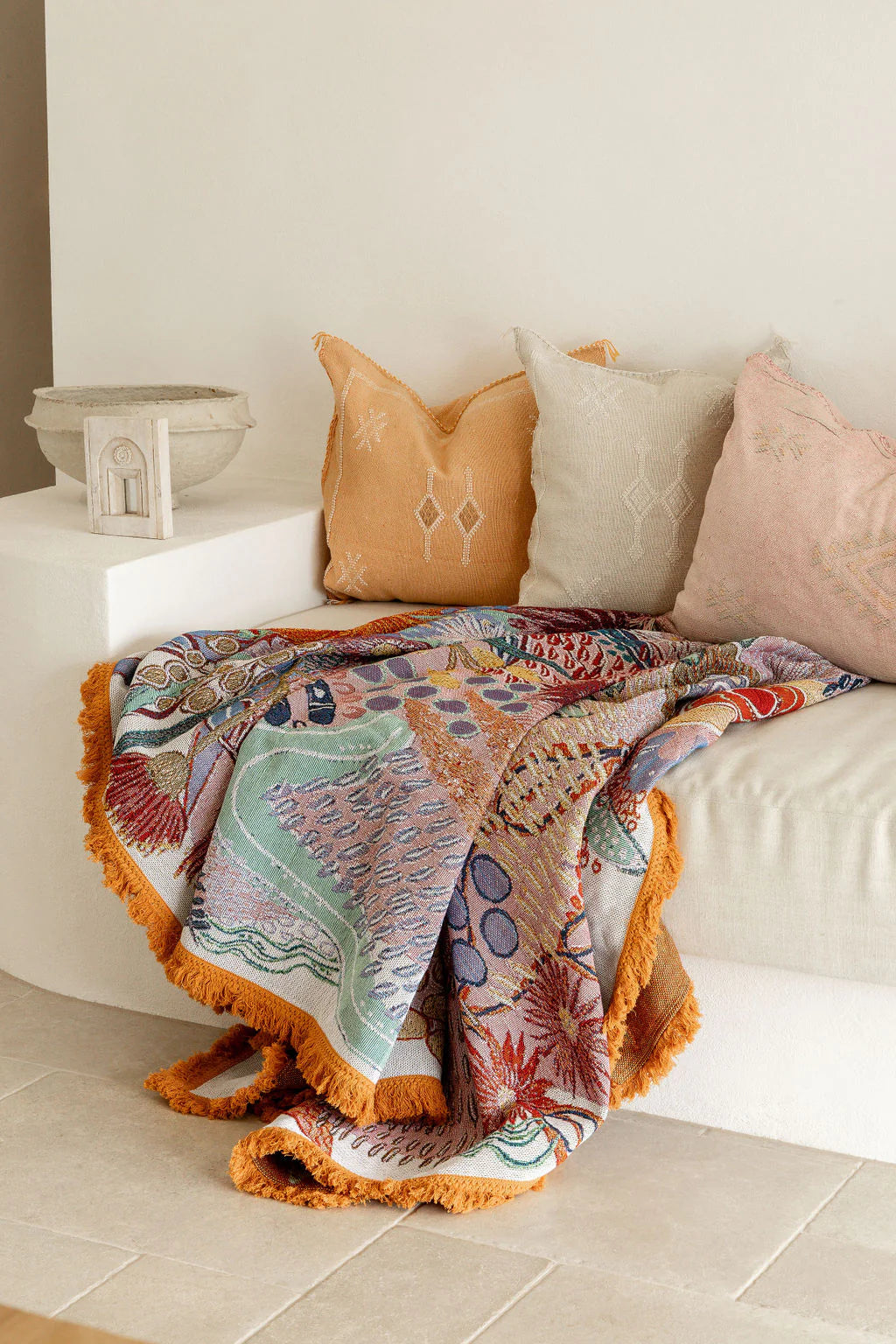 Colorful patterned blanket draped over a sofa with decorative pillows.