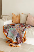 Colorful patterned blanket draped over a sofa with decorative pillows.