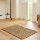 Natural jute rug on a wooden floor with a door in the background