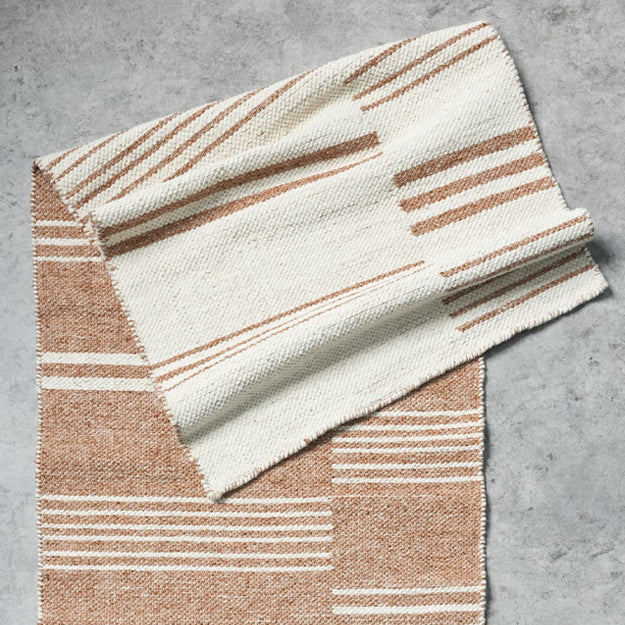 Folded blanket with brown and white striped pattern on a gray surface