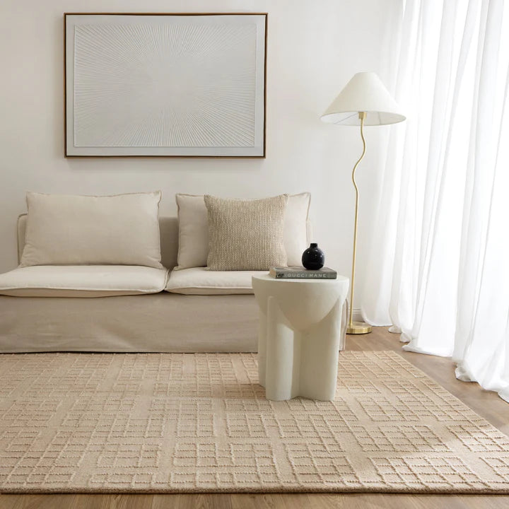 Modern living room with beige sofa, rug, and side table.
