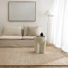 Modern living room with beige sofa, rug, and side table.