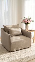 Beige armchair with pillows in a room with a side table and flowers.