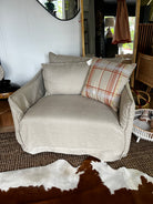 Beige sofa with plaid pillow in a room with wicker furniture and cowhide rug
