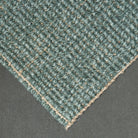 Close-up of a textured green carpet corner on a gray background