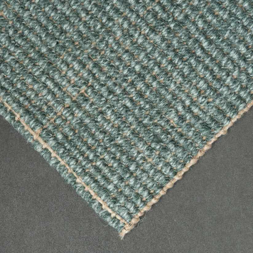 Close-up of a textured green carpet corner on a gray background