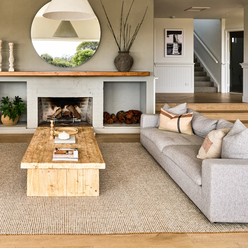 Living room with a fireplace, gray sofa, wooden coffee table, and decorative elements.