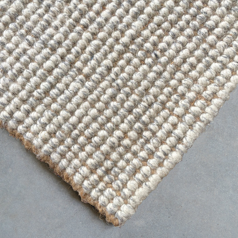 Close-up of a textured beige rug on a gray surface