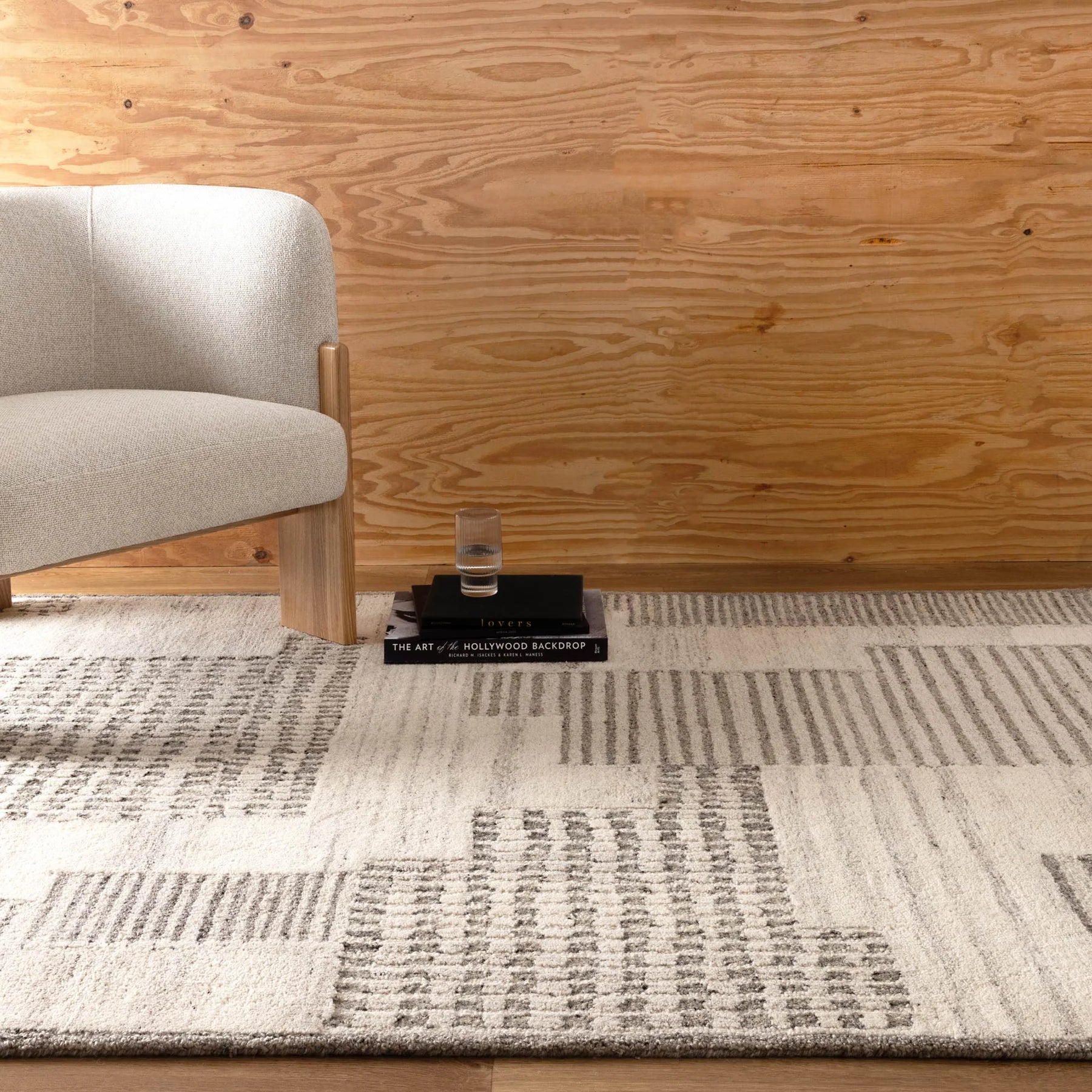 Rug with geometric pattern in a room with wooden wall and chair.