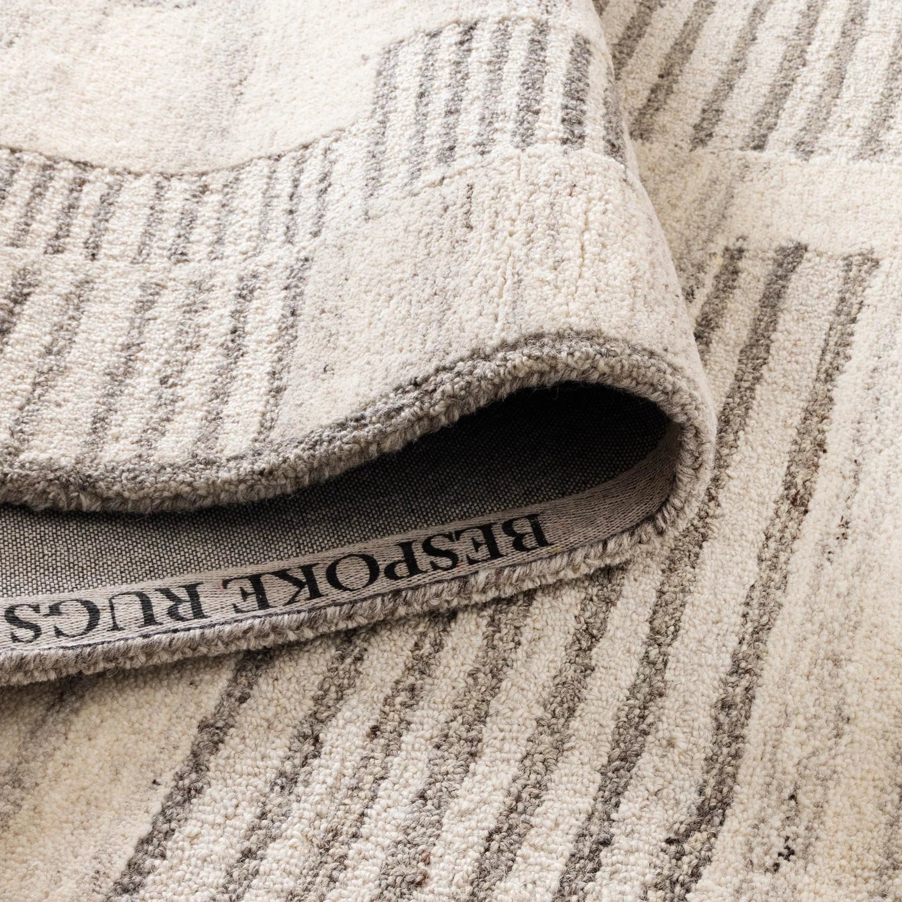 Close-up of a textured rug with striped pattern and 'Bespoke Rugs' label.