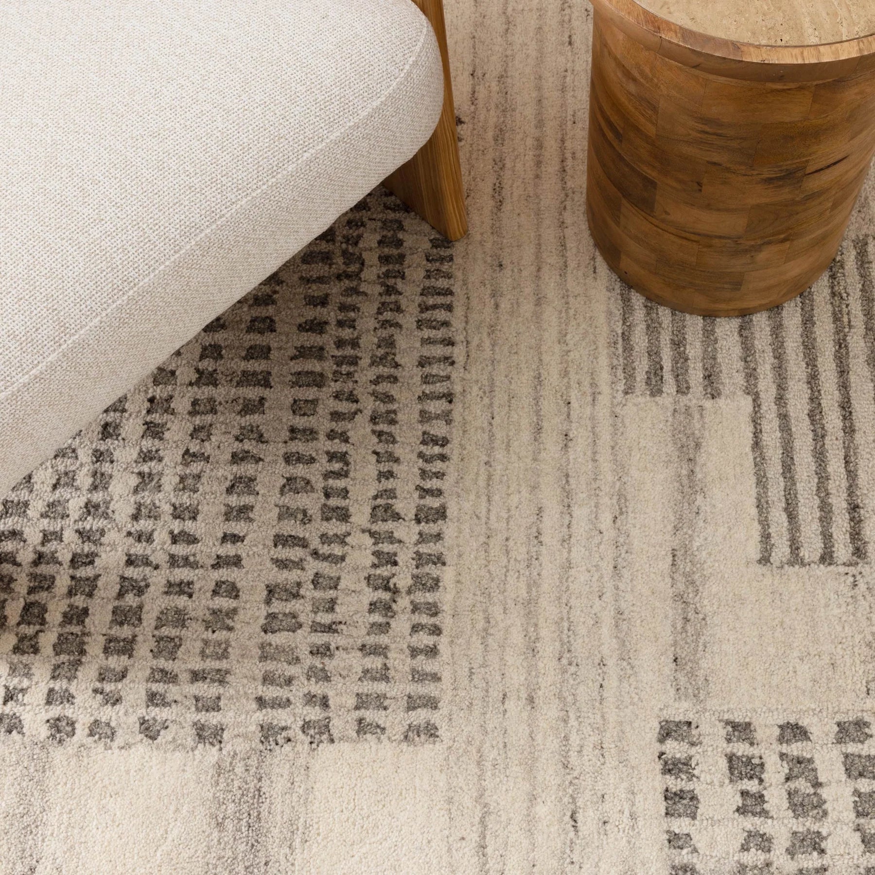 Patterned rug with a chair and wooden side table on a neutral background
