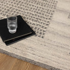 Glass of water and black book on a textured gray and beige rug
