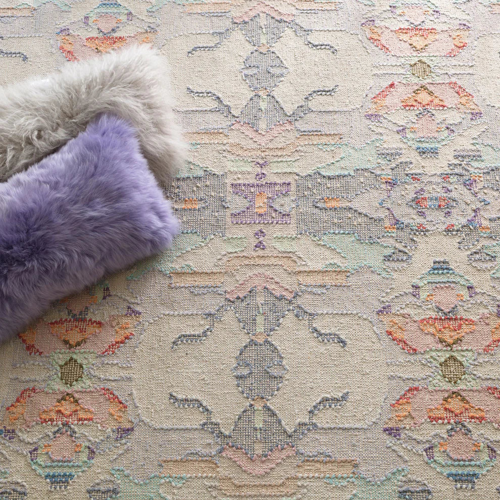 Patterned rug with a fluffy gray pillow and a purple pillow on top