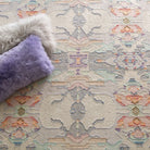 Patterned rug with a fluffy gray pillow and a purple pillow on top