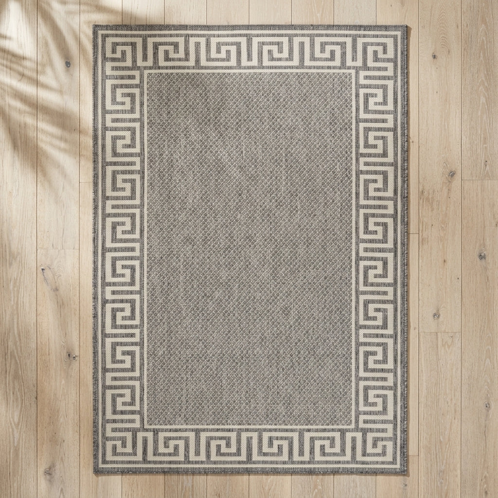 Gray rug with a Greek key border on a wooden floor
