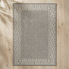 Gray rug with a Greek key border on a wooden floor