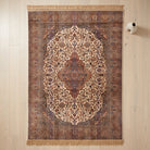 An ornate traditional area rug with a central medallion and intricate floral patterns, displayed flat on a light wood plank floor next to a small white wall-mounted vase.