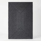 A dark charcoal gray textured area rug with a raised geometric diamond pattern, shown from a top-down perspective on a light gray background.