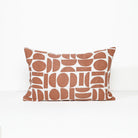 A rectangular throw pillow with a terracotta rust and white geometric pattern, photographed against a clean white background.