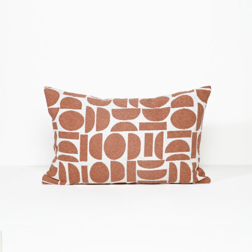 A rectangular throw pillow with a terracotta rust and white geometric pattern, photographed against a clean white background.