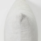 A close-up of a light gray ribbed fabric cushion or pillow against a plain white background.