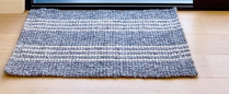 Textured gray doormat on a wooden floor