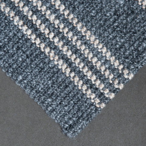 Close-up of a textured blue and white patterned rug on a dark surface