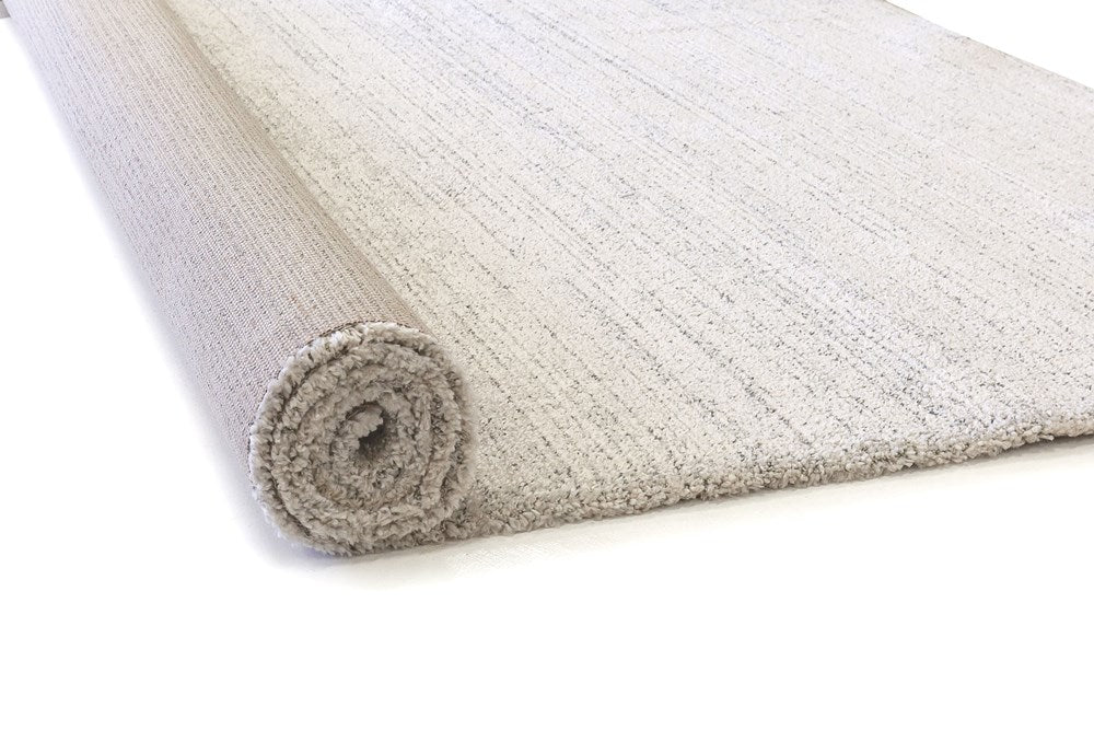 Image of the Cumulus Rug in Stone color rolled up, demonstrating its flexibility and ease of handling for transport or storage.