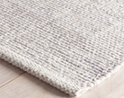 Close-up of a textured gray rug on a light wooden floor