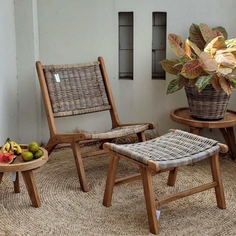 Wicker chair and ottoman set with a small table and plant in a room.
