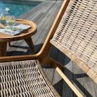 Wicker chair on a wooden deck with a pool in the background