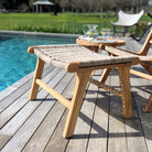 Wooden stool with woven seat on a wooden deck by a pool