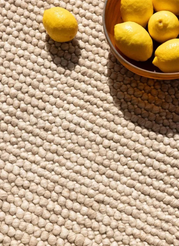 Beige textured rug with lemons on and around it