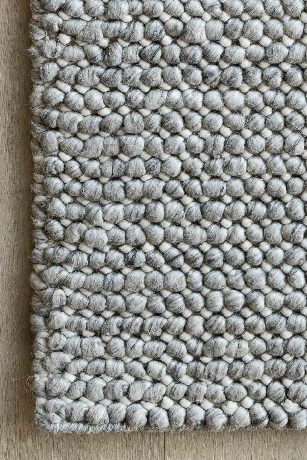 Textured gray rug with a pattern on a wooden floor