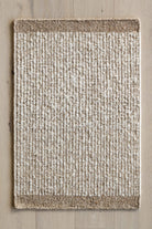 Textured area rug with a natural color palette on a wooden floor.