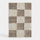 A rectangular shag area rug with a checkerboard pattern in taupe and cream, shown against a plain light gray background.