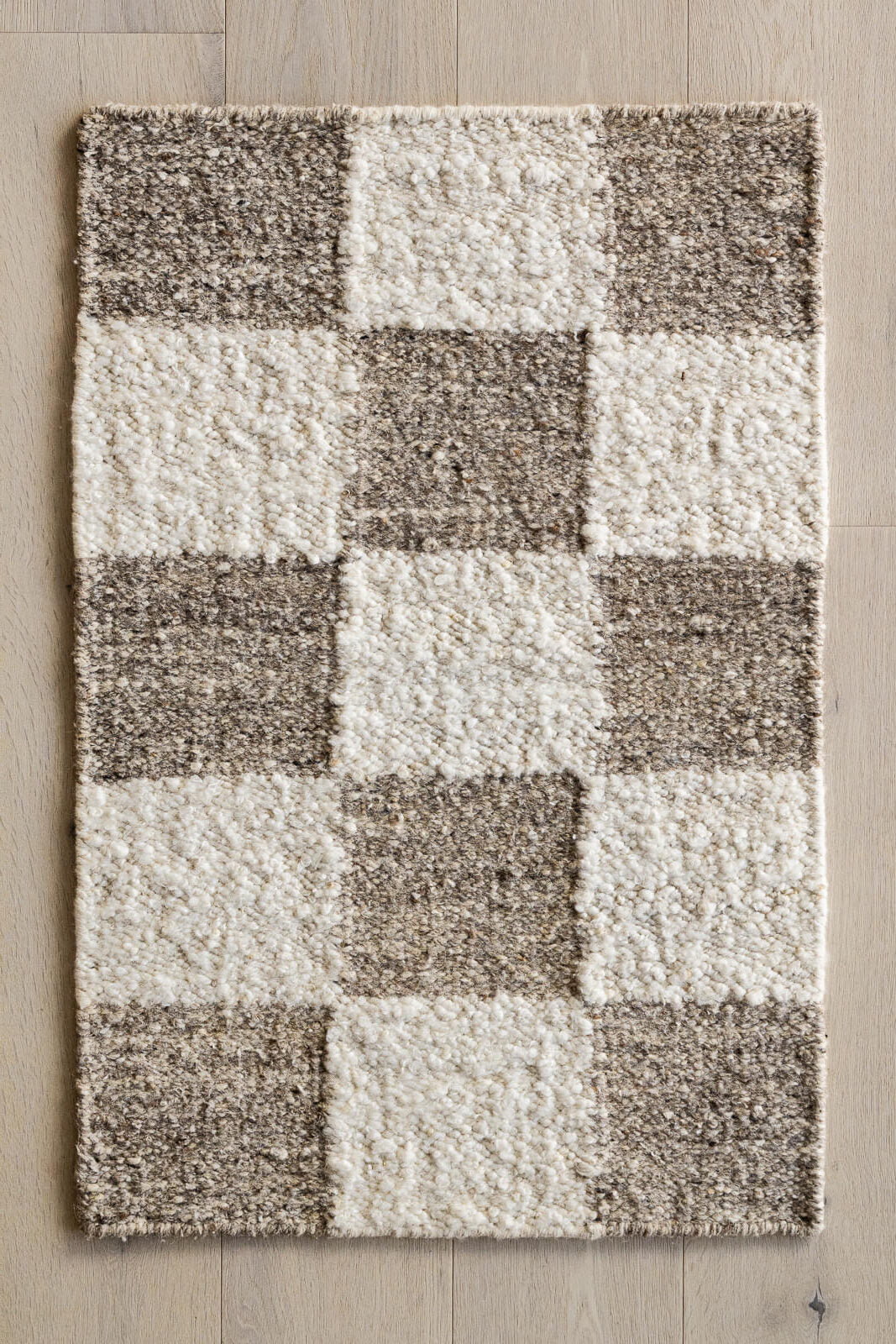 Checkered pattern rug with brown and white squares on a wooden floor.