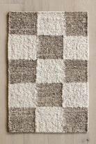 Checkered pattern rug with brown and white squares on a wooden floor.
