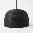 A black woven pendant light shade with a textured, ribbed pattern, suspended by a thin black cord against a plain white background.