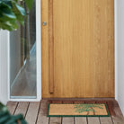Palm tree door mat on timber decking in front of modern door way