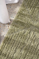Close-up of a textured green rug on a stone floor.