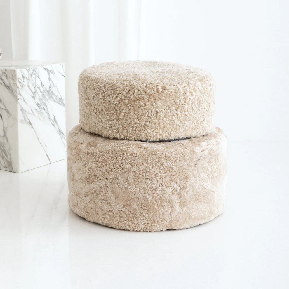 Two round, beige textured ottomans on a white background