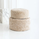 Two round, beige textured ottomans on a white background