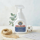 Spray bottle of Definitive Edge Fabric & Rug Guard on a neutral background with decorative elements.