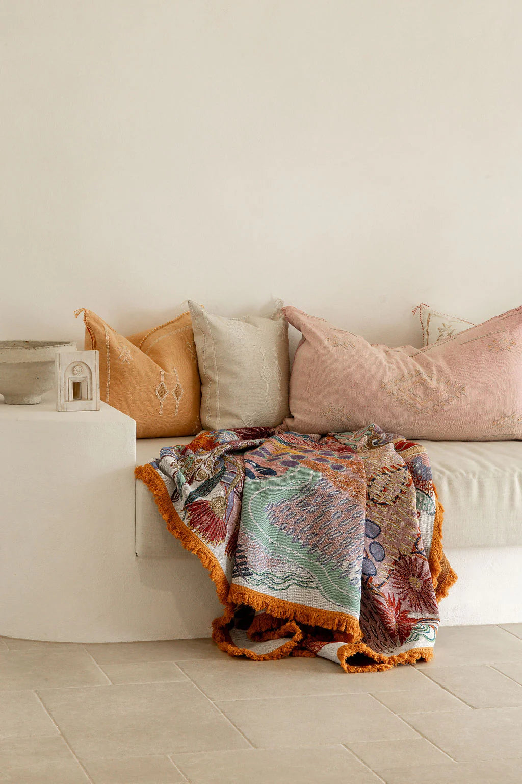 Colorful patterned blanket draped over a white sofa with decorative pillows.