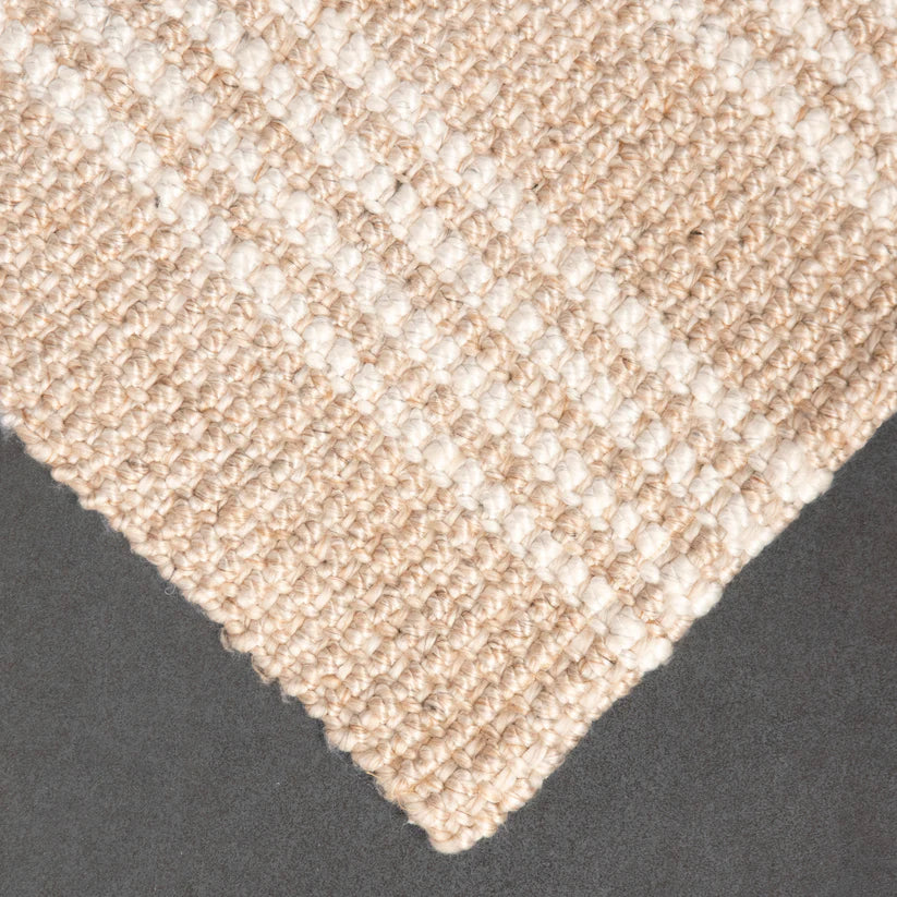 Close-up of a textured beige carpet corner on a dark surface