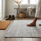 Person walking on a textured rug in a room with a wooden bench and wicker basket.
